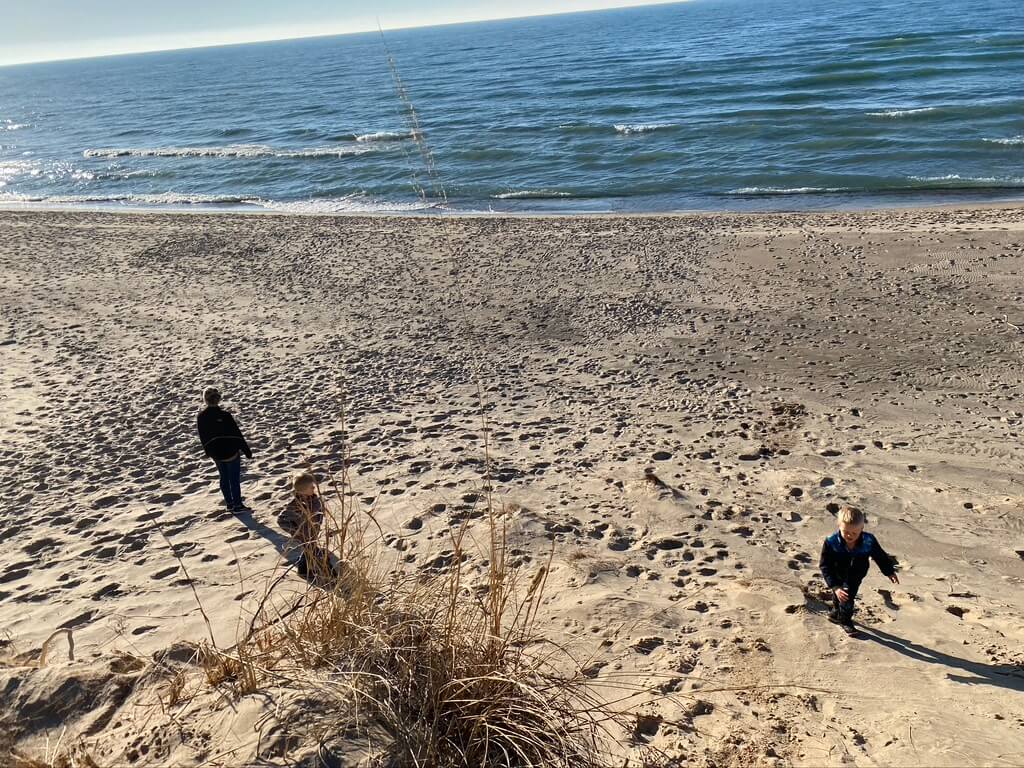 A picture of kids playing on the dunes at Grand Mere State Park in Stevensville, Michigan. The lake in the background. 