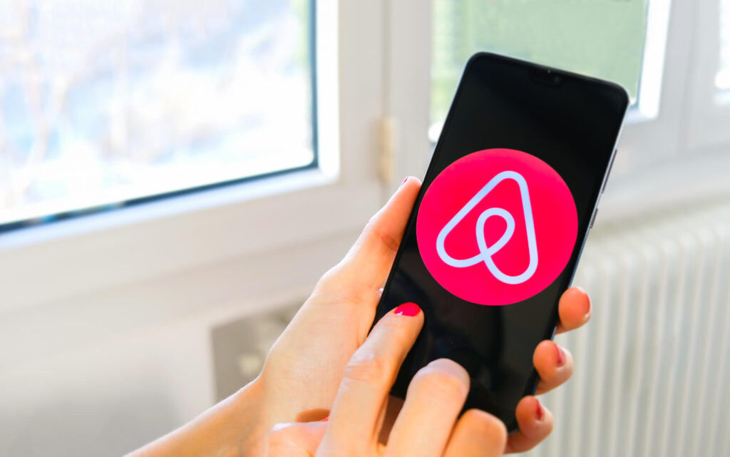 An image of someone holding a phone with an Airbnb logo on it. 
